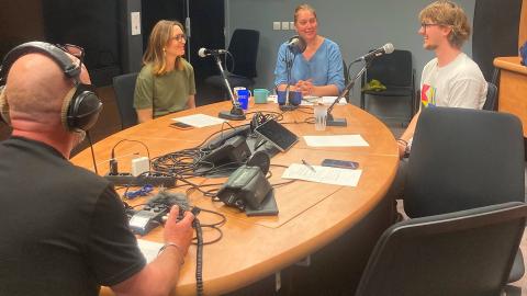 Deux ingénieures pédagogiques et le réalisateur de projets audiovisuels pédagogiques de la DAP sont réunis autour d'une table ovale, en compagnie d'un étudiant. Devant elles et eux se trouvent des micros et des documents puisqu'elles et ils sont en train d'enregistrer un podcast.