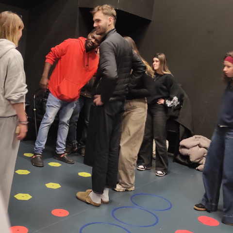 Photo d’étudiantes et étudiants utilisant des cerceaux bleus et des disques colorés disposés au sol. 