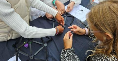 Photo d'un groupe d'enfants en train d'assembler les barres d'un dôme géodésique en plastique