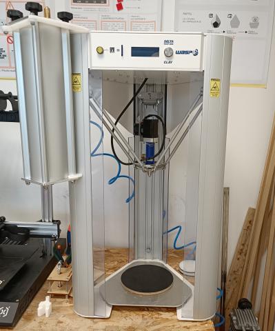Photo d'une imprimante 3D spécifiquement conçue pour la céramique : elle est en forme de colonne triangulaire, d’environ 70 centimètres de haut
